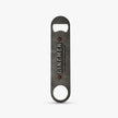 A dark gray metal bottle opener with a distressed finish, featuring the text 'LINEMEN' and 'GRADUATE PEACH COUNTY AMERICA' with red star accents, shown on a light gray background.