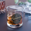 Glass of whiskey with a 'Carpenter' brand label on a dark surface