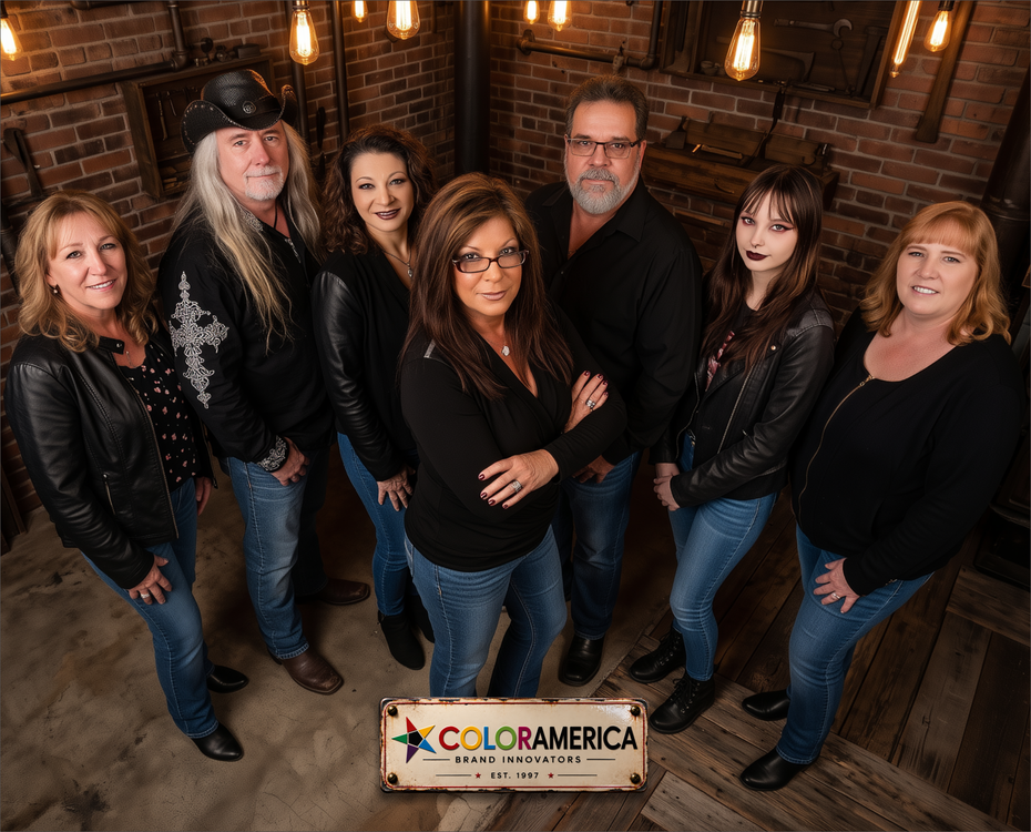 A group of seven people posing together in a rustic indoor setting with brick walls and hanging light bulbs. A sign at the bottom reads ColorAmerica Brand Signature.