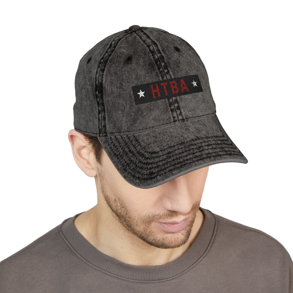 Man wearing a gray cap with 'HTBA' logo on a white background