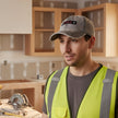 Gray denim cap with 'HTBA' logo worn by a person on a white background