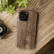 Wooden phone case with 'HTBA' branding on a wooden surface next to a camera and plant.