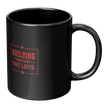 A glossy black ceramic mug with a red printed graphic on the front that reads 'BUILDING SOMETHING THAT LASTS.' with small star accents, shown on a plain white background.