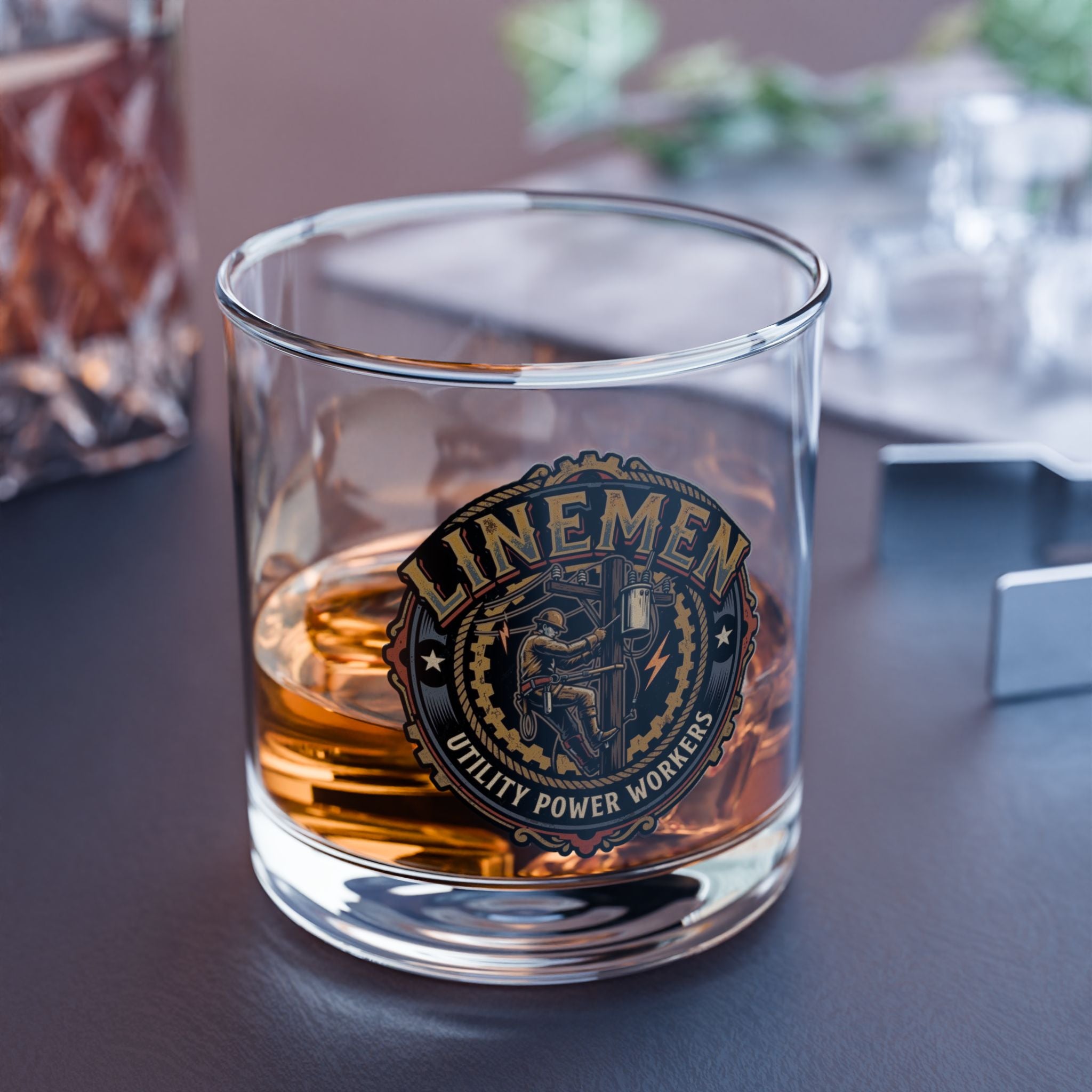 Glass with a 'Linemen' emblem filled with a amber liquid on a dark surface.