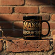 Black mug with decorative text on a brick wall with a trowel and loose brick