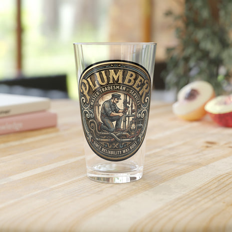 Pint Glass with a 'Plumber' label on a wooden surface