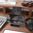 Phone stand on a desk with a keyboard, mouse, and headphones in the background