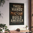 Poster with 'These Hands Build America' text and graphic of clasped hands on a wall above a desk.